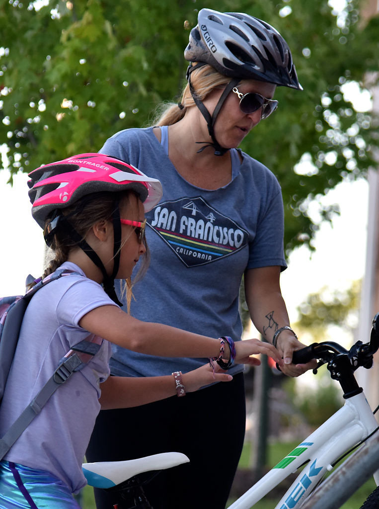 Rigel Oliveri helps her daughter, Shennie Byrne, 8, put her bike on the bike rack before school
